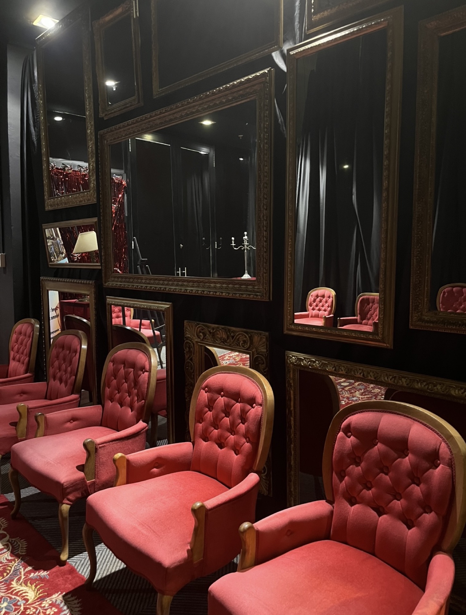 Red upholstered chairs beneath ornate mirrors at Centrestage@Baywest
