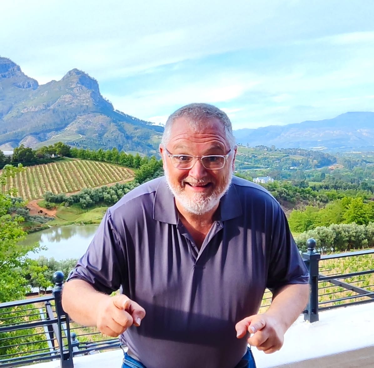 Gary smiling outdoors with vineyards and mountains behind him